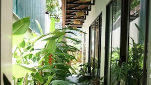 A view through a window with wooden beams, potted plants, and a balcony with a railing. - Tam Coc AppA House (Nam Hoa Lu)