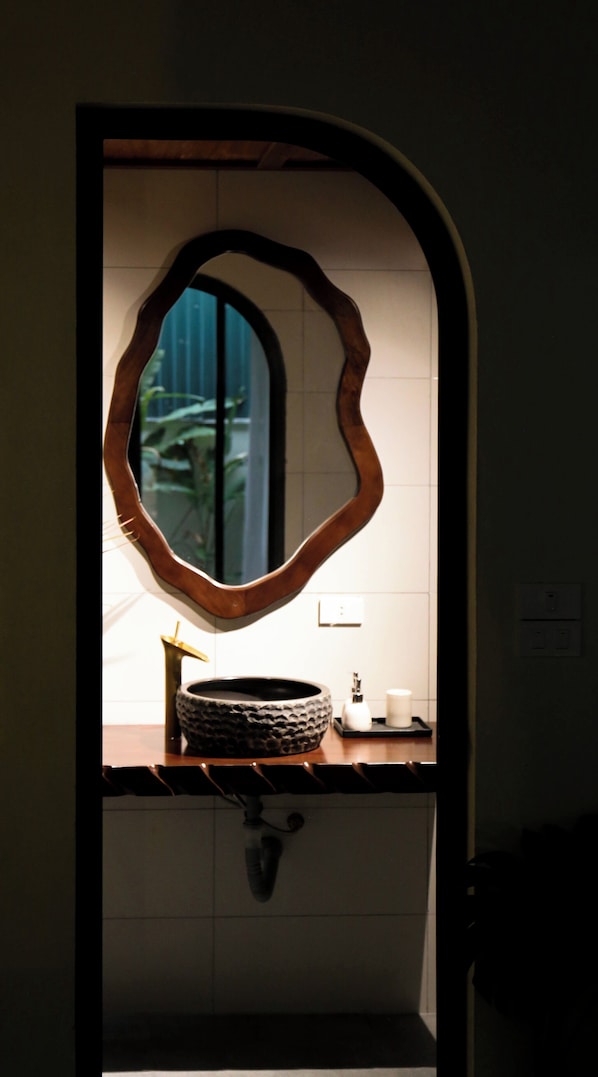 A bathroom with a unique mirror design, a sink, and a window.