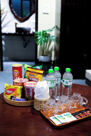 A tray with snacks, drinks, and a bottle of Dasani water on a wooden table.