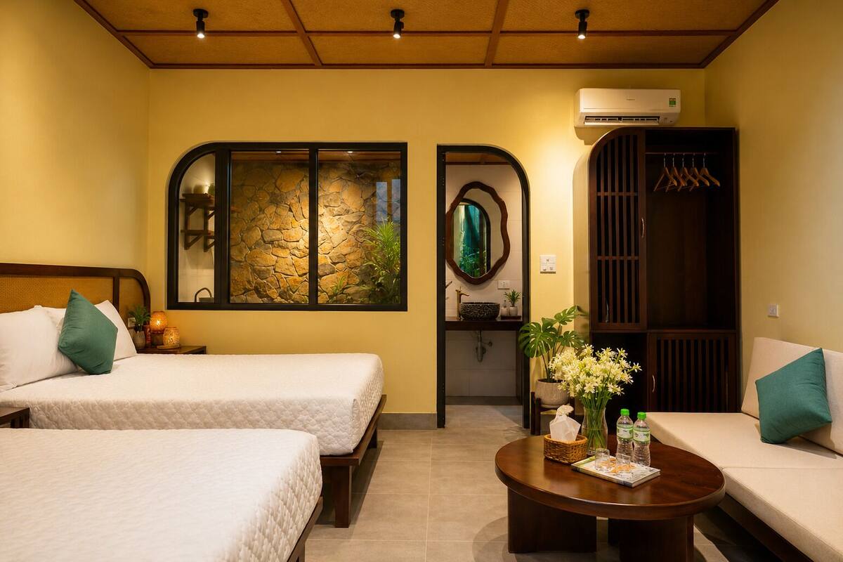 A hotel room with two beds, a sofa, a round coffee table, a mirror, and a wardrobe.