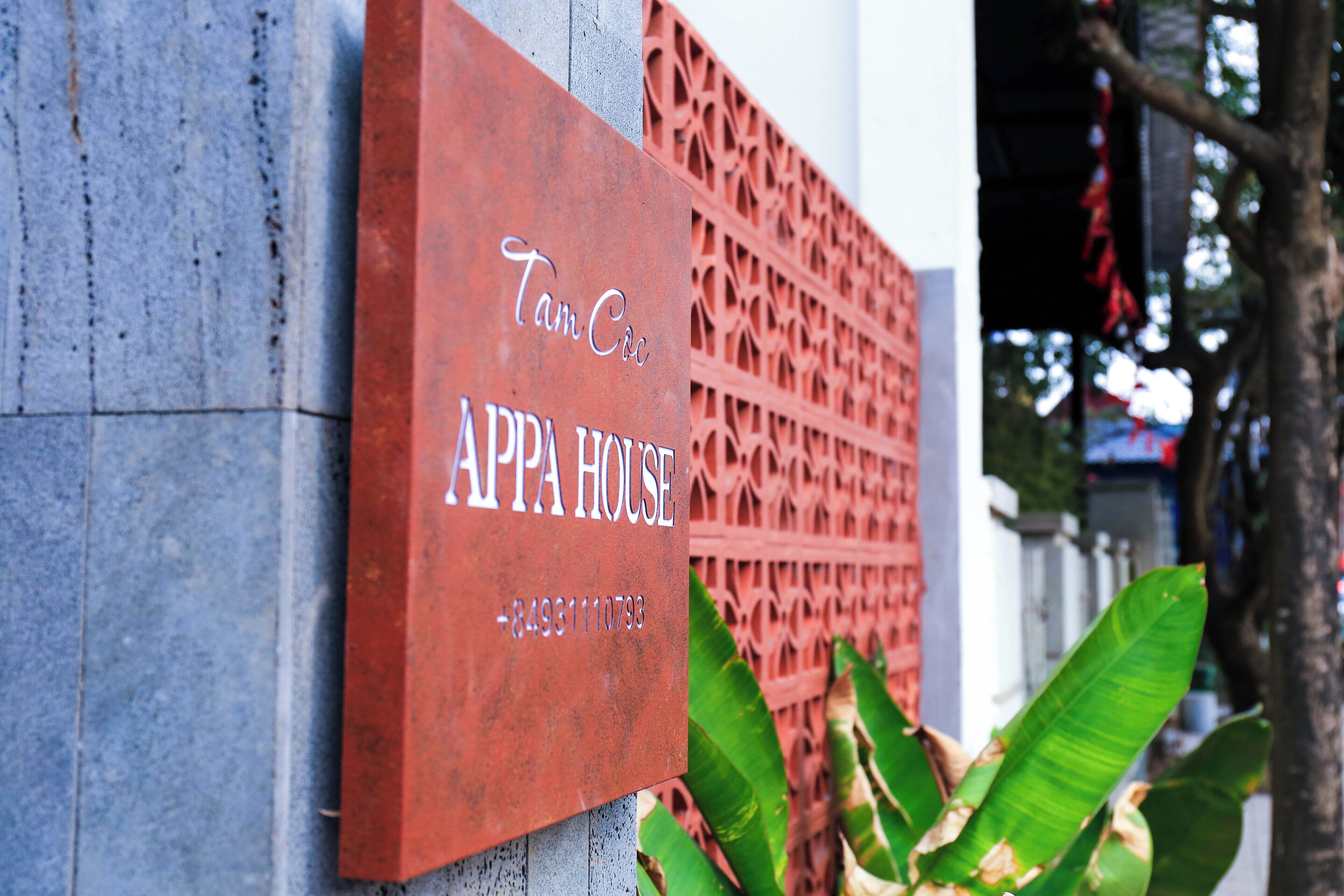 Une enseigne indiquant « Tam Cc Appa House » avec un numéro de téléphone à contacter.