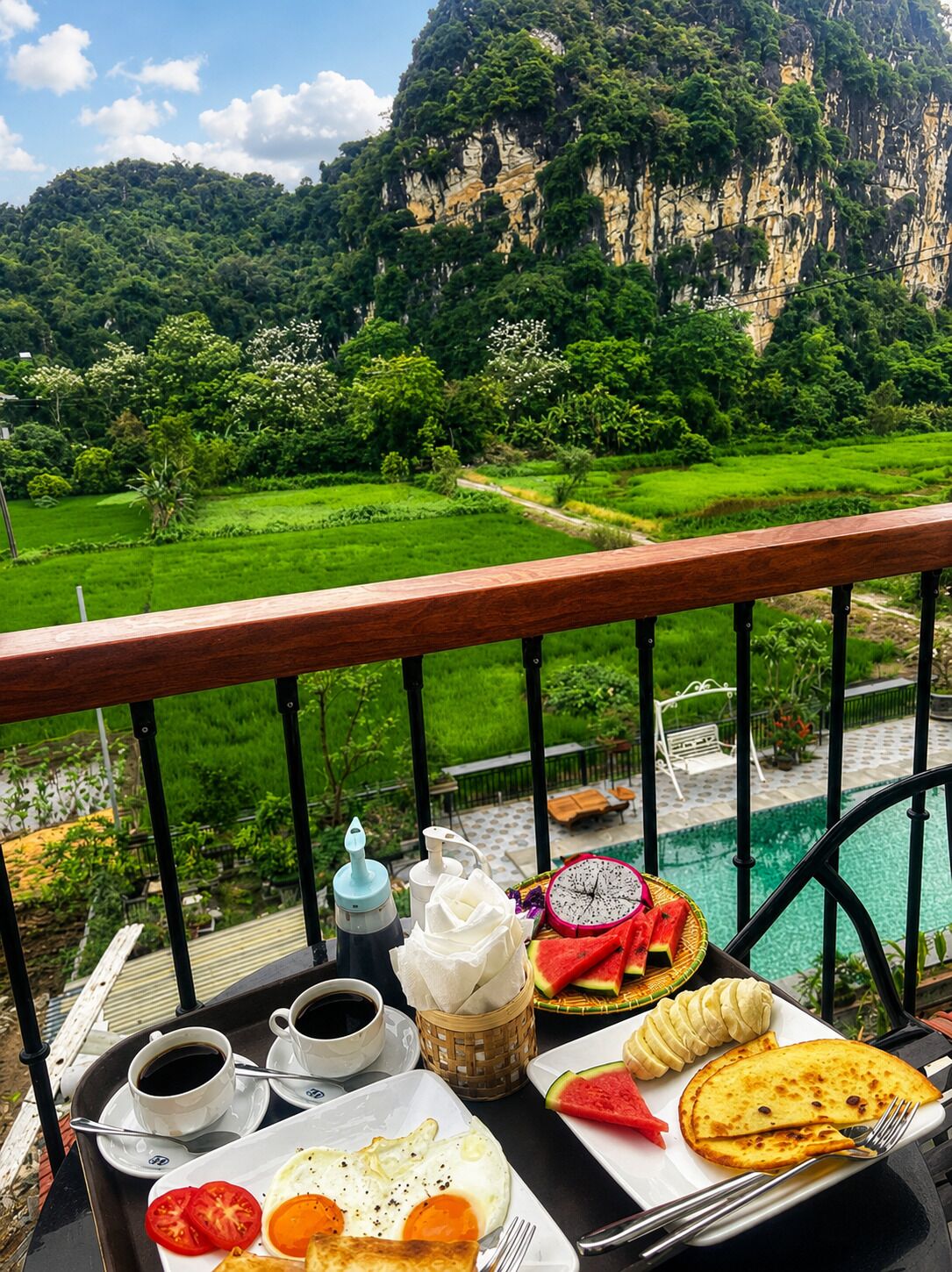 Une table à manger dressée avec des aliments pour le petit-déjeuner, offrant une vue pittoresque sur un paysage verdoyant et une piscine.