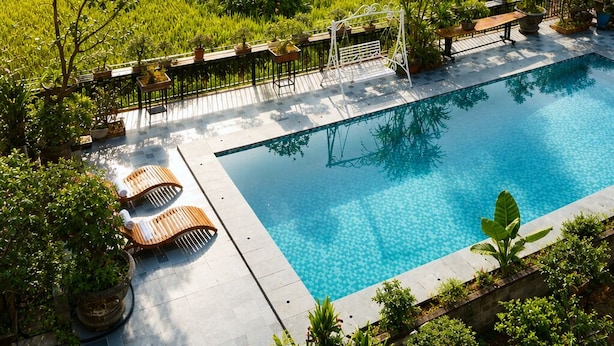 A swimming pool with a view of a lush green landscape and a rocky cliff. - Tam Coc AppA House (Nam Hoa Lu)