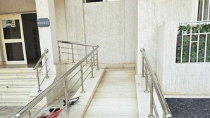 Un escalier en marbre avec des rampes métalliques menant à une entrée.