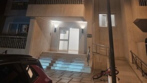 Un immeuble à plusieurs étages, doté d’une entrée bien éclairée, de marches menant à la porte et d’une voiture garée au premier plan.