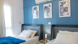 Une chambre d’hôtel avec deux lits, une table de chevet avec une lampe et des œuvres d’art accrochées au mur.