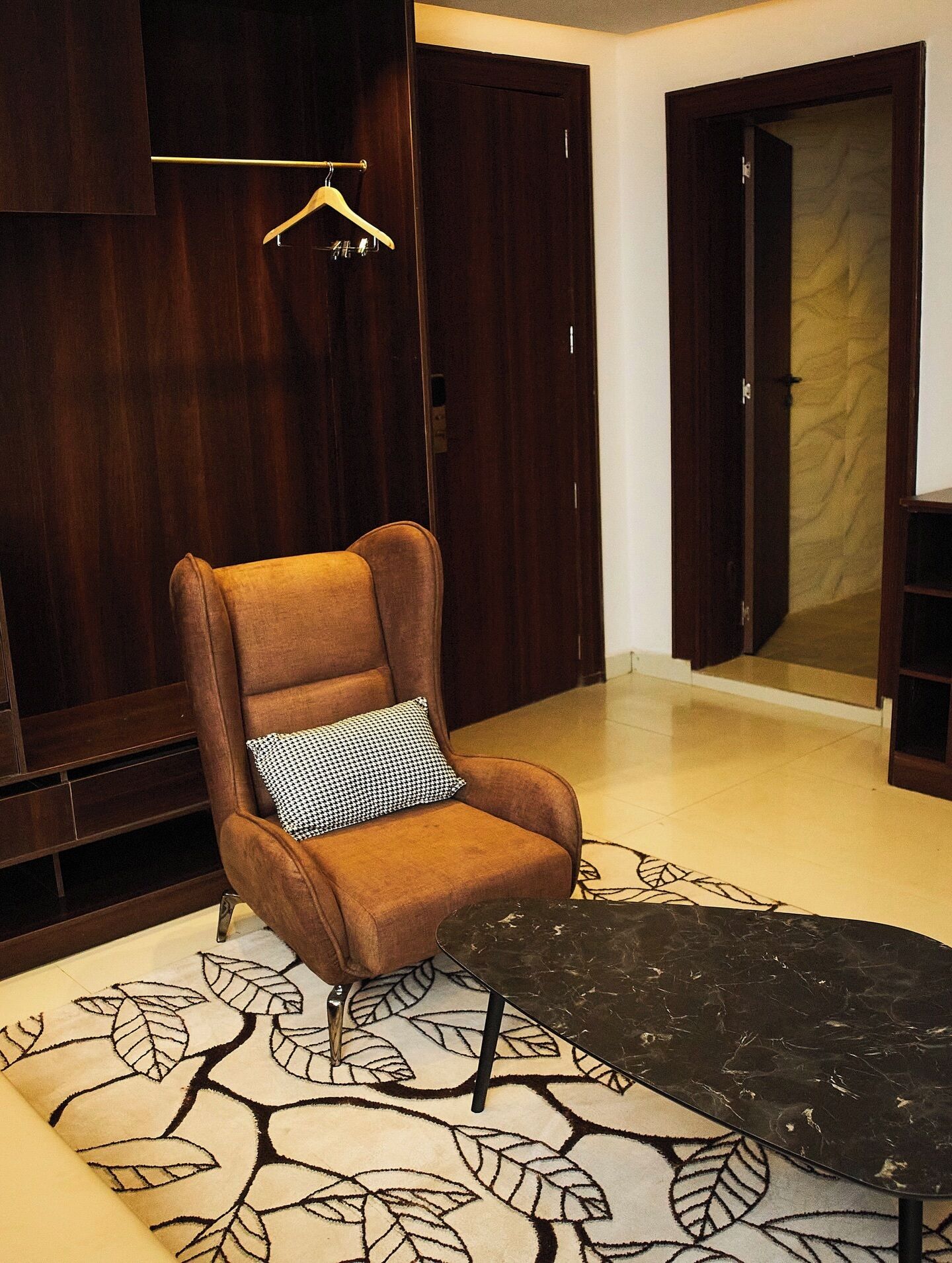 Una habitación con un sillón marrón, un tapete estampado y muebles de madera.