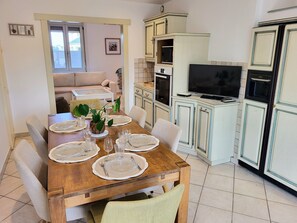 Un coin repas avec une table en bois dressée pour six personnes, entourée de chaises.