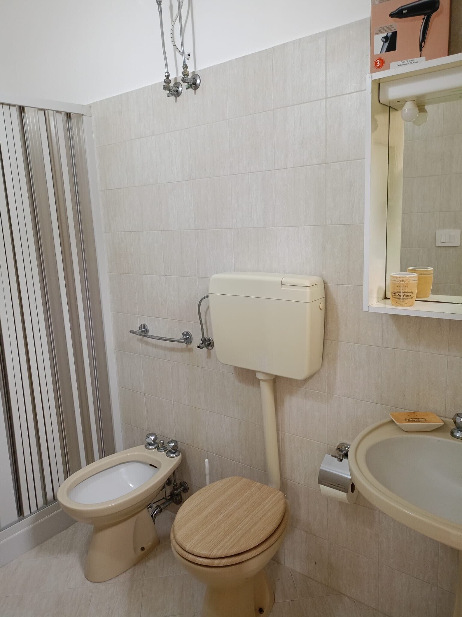 A bathroom with a toilet, bidet, and sink, with a mirror above the sink.
