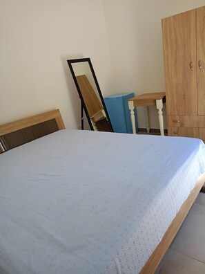 Une pièce comprenant un lit, une armoire en bois, un meuble bleu et une chaise en bois.