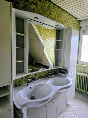 Ein Badezimmer mit einem Doppelwaschbecken, einem Spiegel und einer Wand mit grünem Muster.