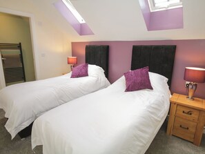Une chambre d’hôtel avec deux lits, une table de chevet avec une lampe, un tiroir en bois et une fenêtre donnant sur un paysage agréable.