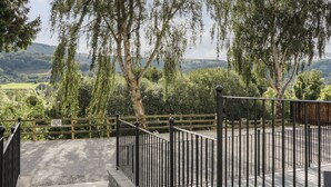 A fenced outdoor area with a gravel path leading to a wooden structure. - Sun Trevor Barns 2 (Llangollen)