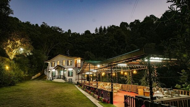 A two-story building with a covered outdoor dining area, surrounded by greenery. - Royal Stay In The Nature's Lap (Shoghi)