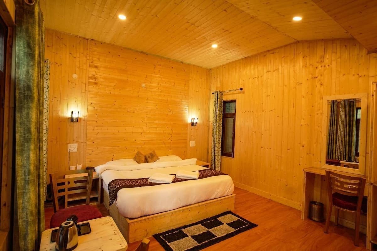 A wooden-paneled room with a bed, bedside table, and a desk with a chair.
