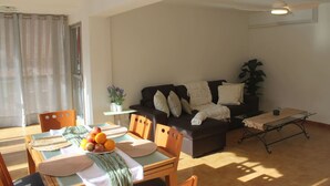 Un salon avec un canapé, une table à manger et des chaises, un ventilateur de plafond et une plante en pot.