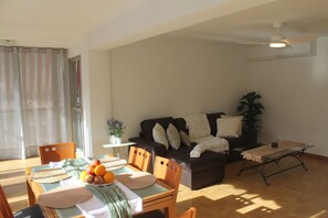 A living room with a sofa, a dining table with chairs, a ceiling fan, and a potted plant. - Agua Azul · Reformado · 5 Pax · Parking/wifi (Benidorm)