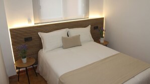 Un lit bien fait, avec une tête de lit, deux tables de chevet et une fenêtre au-dessus du lit.