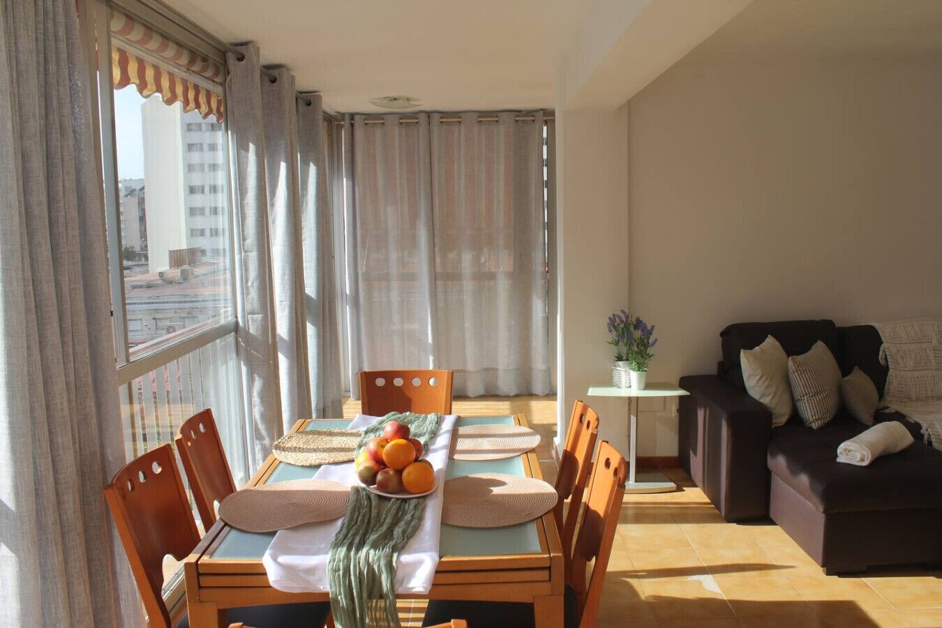 Een eetgedeelte met een tafel voor vier personen, een bank en een potplant.