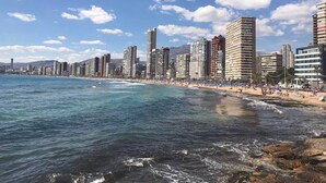 Un paisaje urbano costero con rascacielos, una playa y cielos despejados.