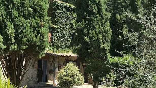 Ein Steinhaus mit einer kleinen Tür und einem Fenster, umgeben von dichtem Grün.