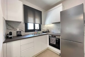 A modern kitchen with white cabinets, a stainless steel refrigerator, a built-in oven, and a marble backsplash. - Athenean Modern Escape near Marina Flisvos-G3 (Paleo Faliro)