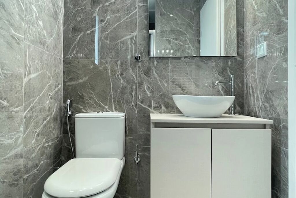 Ein Badezimmer mit Toilette, einem Waschbecken mit einer Aufsatzwaschbecken und einem Schrank.