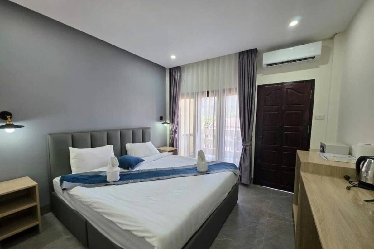 Une chambre d’hôtel moderne équipée d’un grand lit, de tables de chevet, d’un bureau et d’un appareil de climatisation.