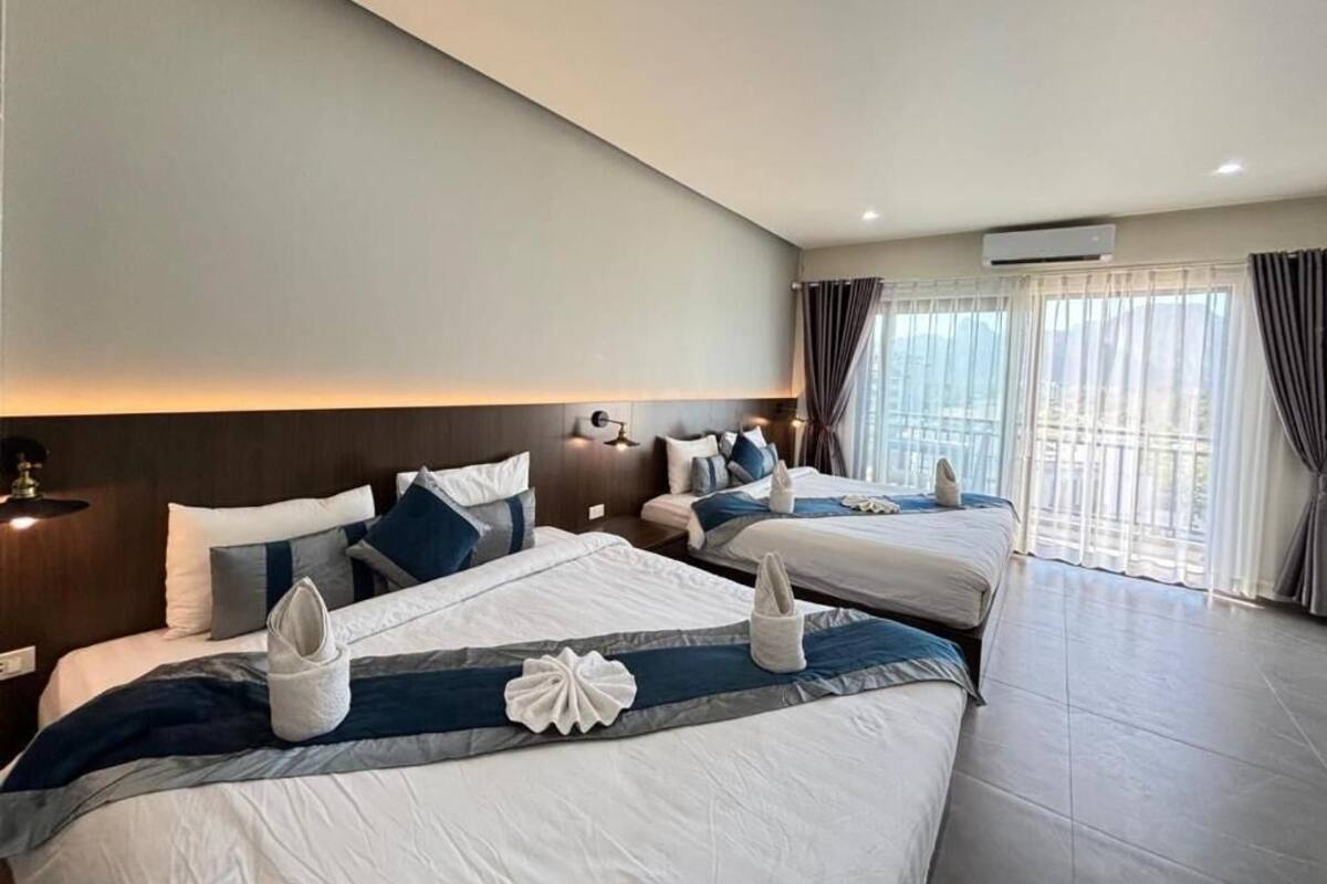 Une chambre d’hôtel avec deux lits, une grande fenêtre avec des rideaux et un design moderne.