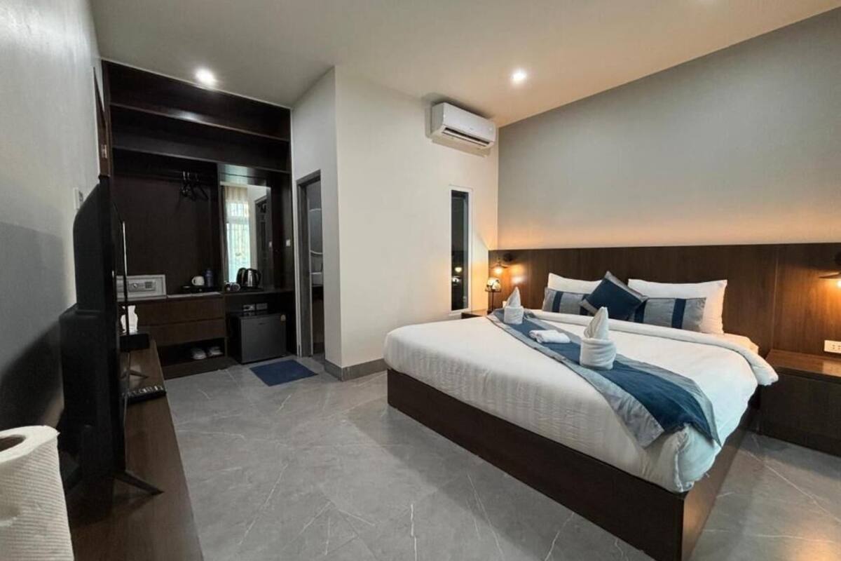 Une chambre d’hôtel moderne avec un grand lit, une armoire intégrée, un petit bureau et une salle de bain.