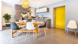 Une cuisine moderne avec un coin repas, une porte jaune et un luminaire suspendu.