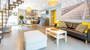 Un salon moderne comprenant un canapé, un pouf, une table basse et un coin repas.
