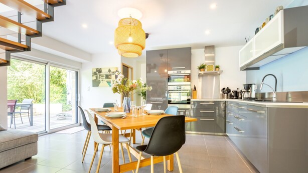 Une cuisine moderne avec un coin repas, des appareils électroménagers en acier inoxydable et un escalier.