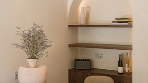 A modern room with a wooden desk, a white vase with flowers, a bookshelf, and a wine bottle. - Eteon Living Suites (Chania)