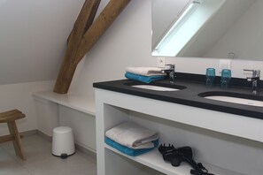 Casa de banho moderna com duas pias, espelho e uma viga de madeira.