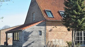 A building with a sloped roof, a small window, and a door. - Holiday home for 8 people on a renovated farm (sijsele)