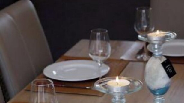 A dining area with a table set for two, a candle, and a wine glass. - Holiday home for 8 people on a renovated farm (sijsele)