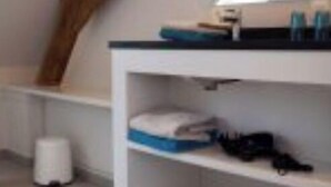 A room with a sloped ceiling, a white desk with a mirror, and a shelf with various items. - Holiday home for 8 people on a renovated farm (sijsele)
