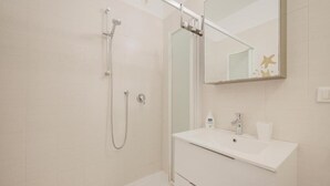 Un baño moderno con ducha, lavabo y espejo.