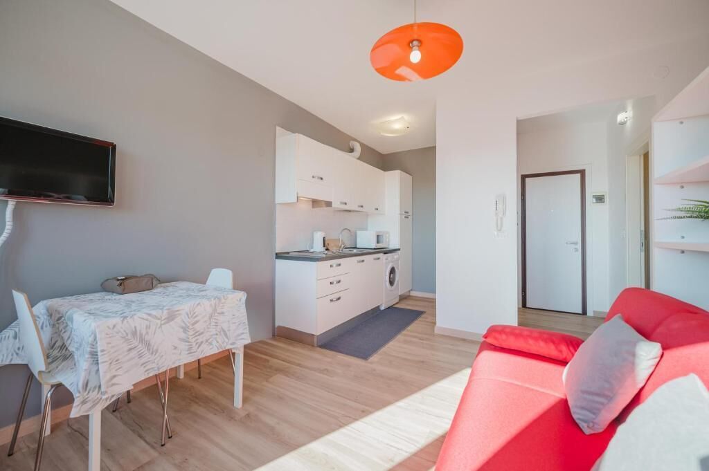 Un espacio habitable moderno con comedor, cocina y un sofá rojo.