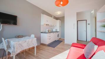 Un espacio habitable moderno con comedor, cocina y un sofá rojo.