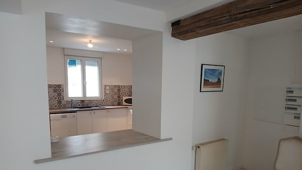 A kitchen with a window, a radiator, and a chair.