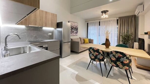 Een moderne keuken met een inbouwspoelbak, een eethoek met twee stoelen en een bank.