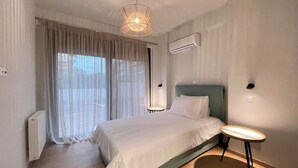 Een hotelkamer met een bed, nachtkastje, hanglamp en airconditioning.