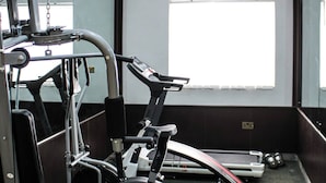 A gym with exercise equipment, a treadmill, and a large window. - Bengerald Hotel And Suites (Abuja)