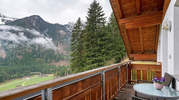 A balcony with a wooden railing, a table with chairs, and a potted plant. - Apartment 'Mair Am Tinkhof Bergwohnung' with Mountain View, Shared Terrace and Wi-Fi (Selva dei Molini)