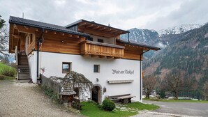 A mountain lodge with a wooden balcony, a stone staircase, and a view of snow-capped mountains. - Apartment 'Mair Am Tinkhof Bergwohnung' with Mountain View, Shared Terrace and Wi-Fi (Selva dei Molini)
