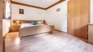 Une chambre à coucher avec un lit en bois, des tables de chevet, une lampe de chevet, un luminaire au plafond et une armoire.