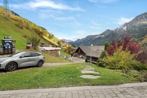 A rural setting with a paved road, a parked car, and a building with a sloped roof.