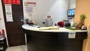 A reception desk with a Paytm sign, a computer, a TV, and a reception area with a signboard. - Townhouse Aiims Kolkata Tanishq Inn (Kalyani)